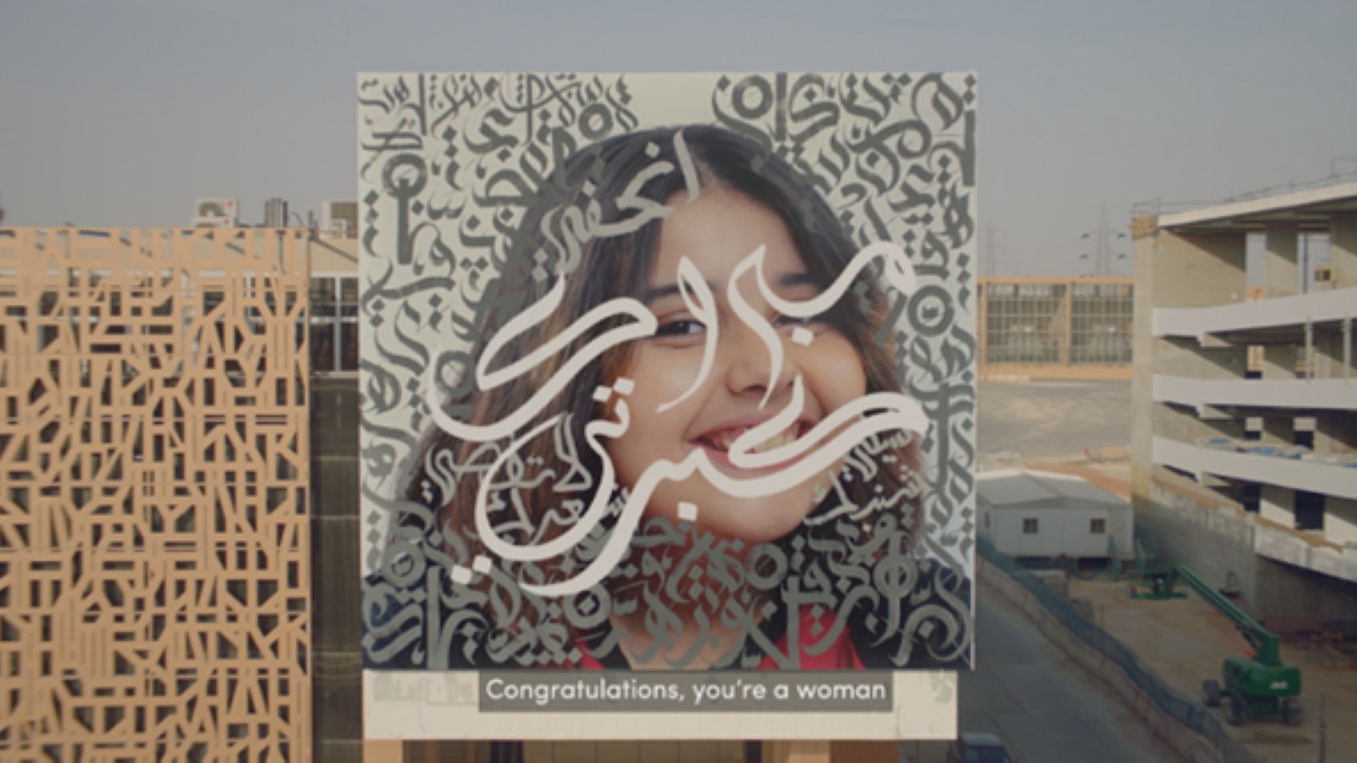 Poster of a girl on the side of a building, with the tagline "Congratulations, you're a woman".
