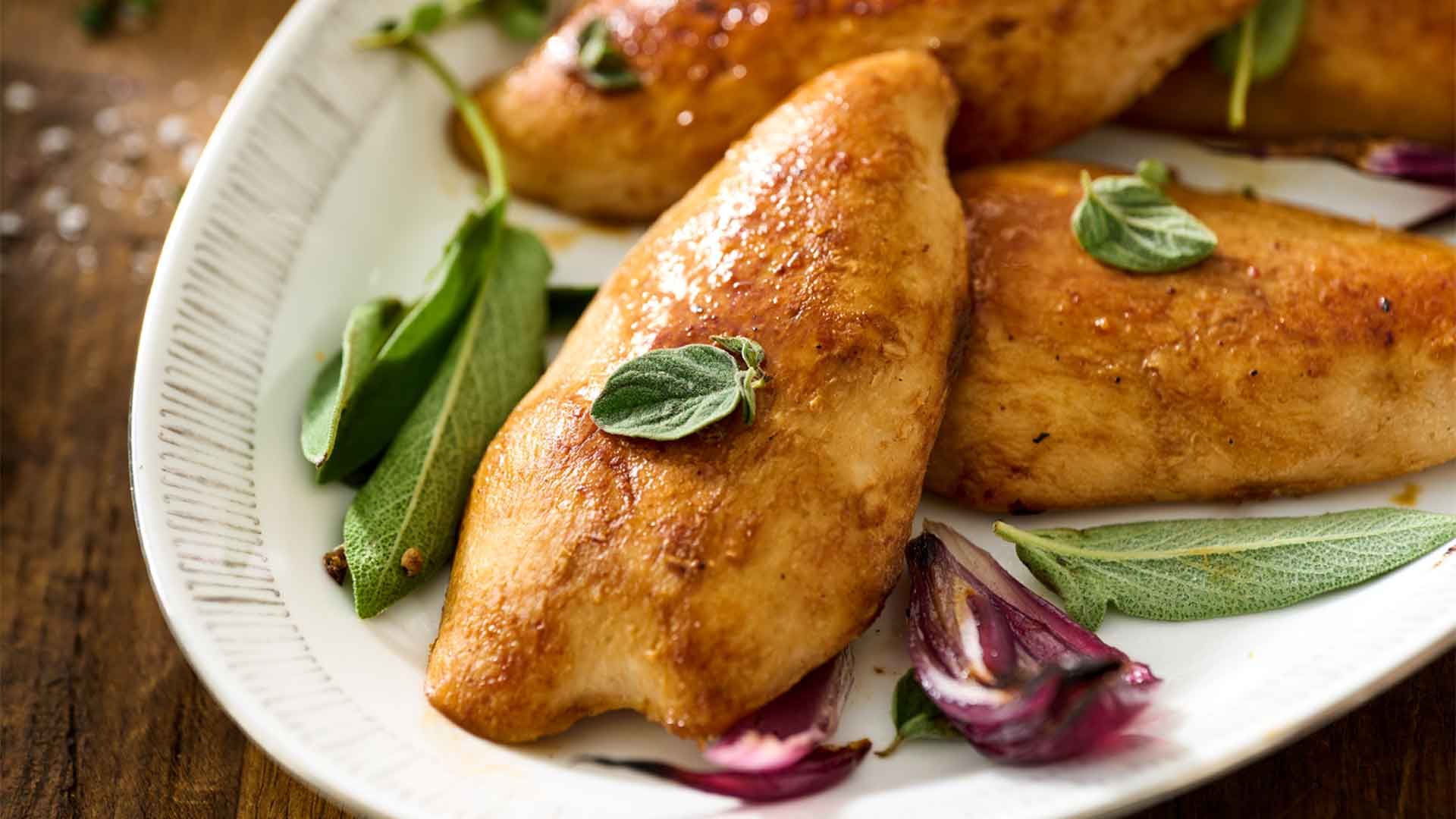 Close-up of three cooked chicken breasts on a plate