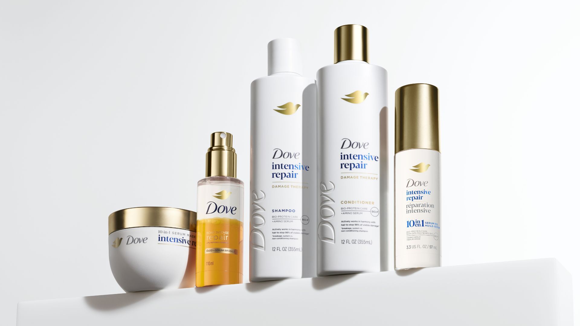 Five products from the Dove Damage Therapy range, designed to repair and strengthen damaged hair. Packaging is white with gold accents.