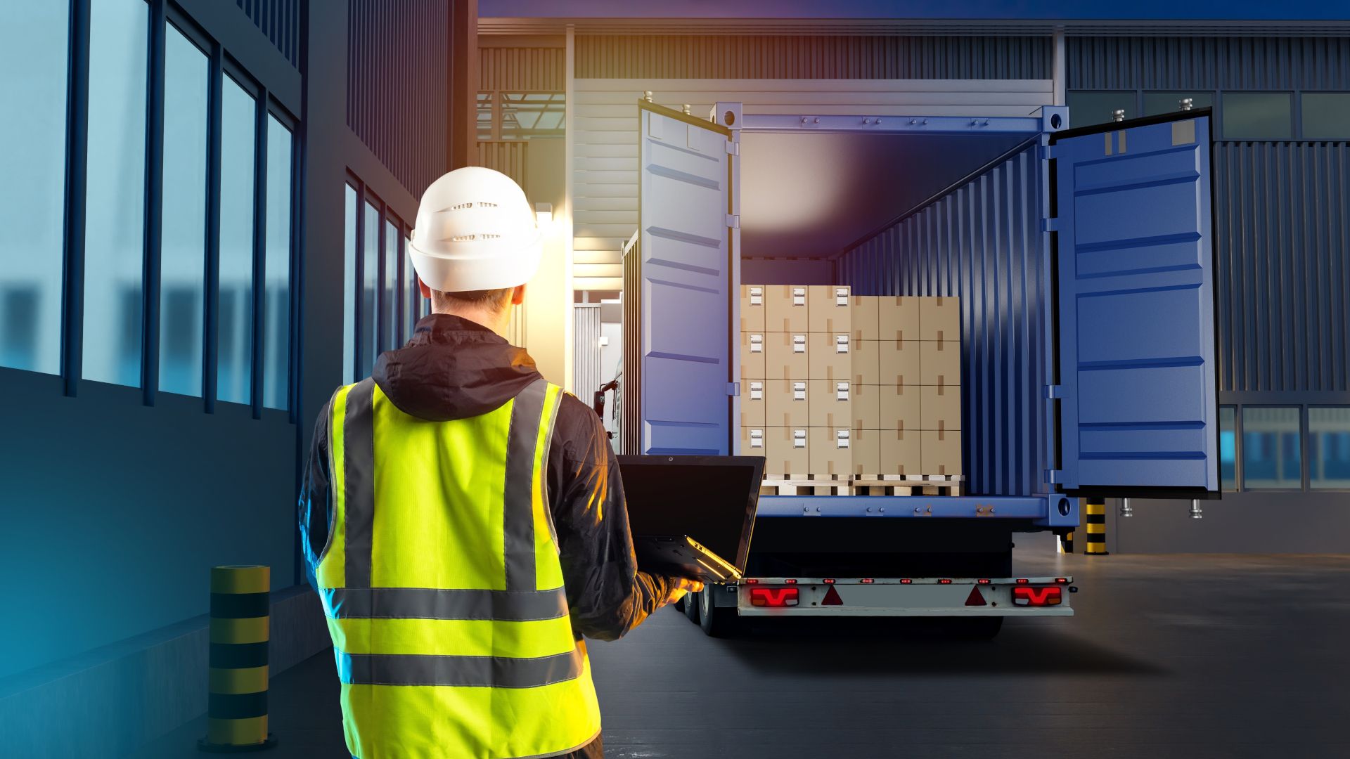 Warehouse worker in hard hat loading a pallet of goods into a truck