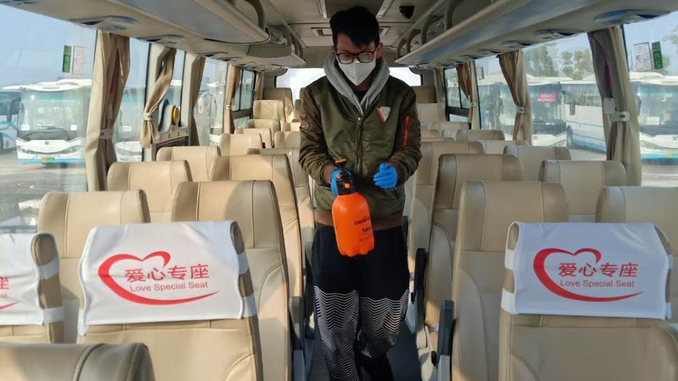 A man walks down the aisle of a bus with cleaning equipment
