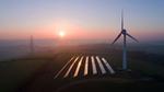 Aerial view of rural landscape showing wind turbine and solar panels in field.